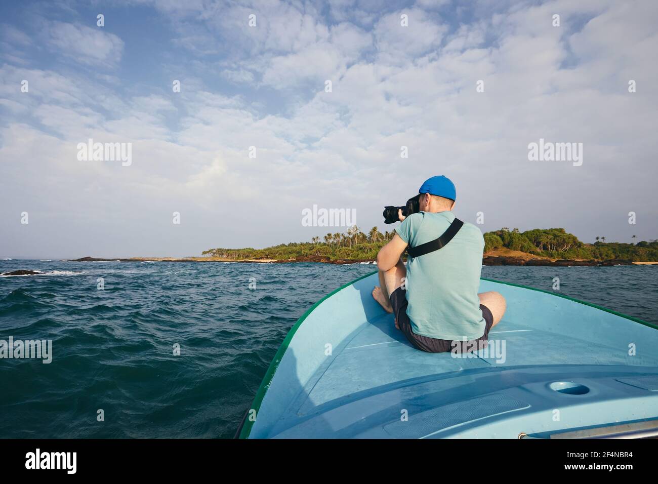 Fotografo seduto in barca. Giovane uomo che fotografa la bellissima costa con palme vicino a Tangalle in Sri Lanka. Foto Stock