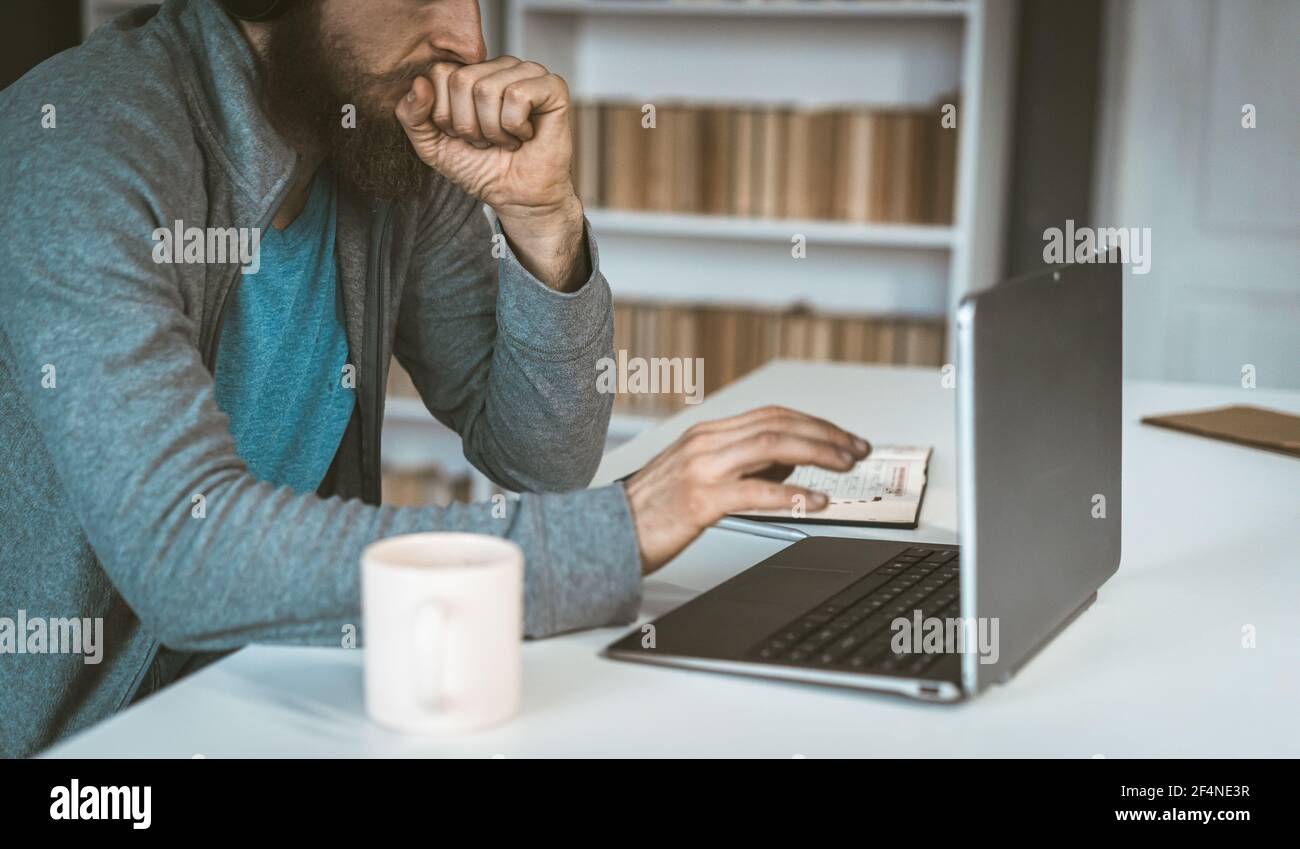 Un uomo pensa di fronte a un computer. Triste europeo lavora su Internet. Il concetto di scelta. Foto Stock
