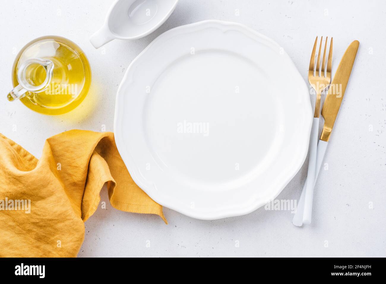 Piatto bianco vuoto, biancheria da tavola gialla e posate dorate. Elegante impostazione della tabella con spazio di copia per testo o disegno Foto Stock
