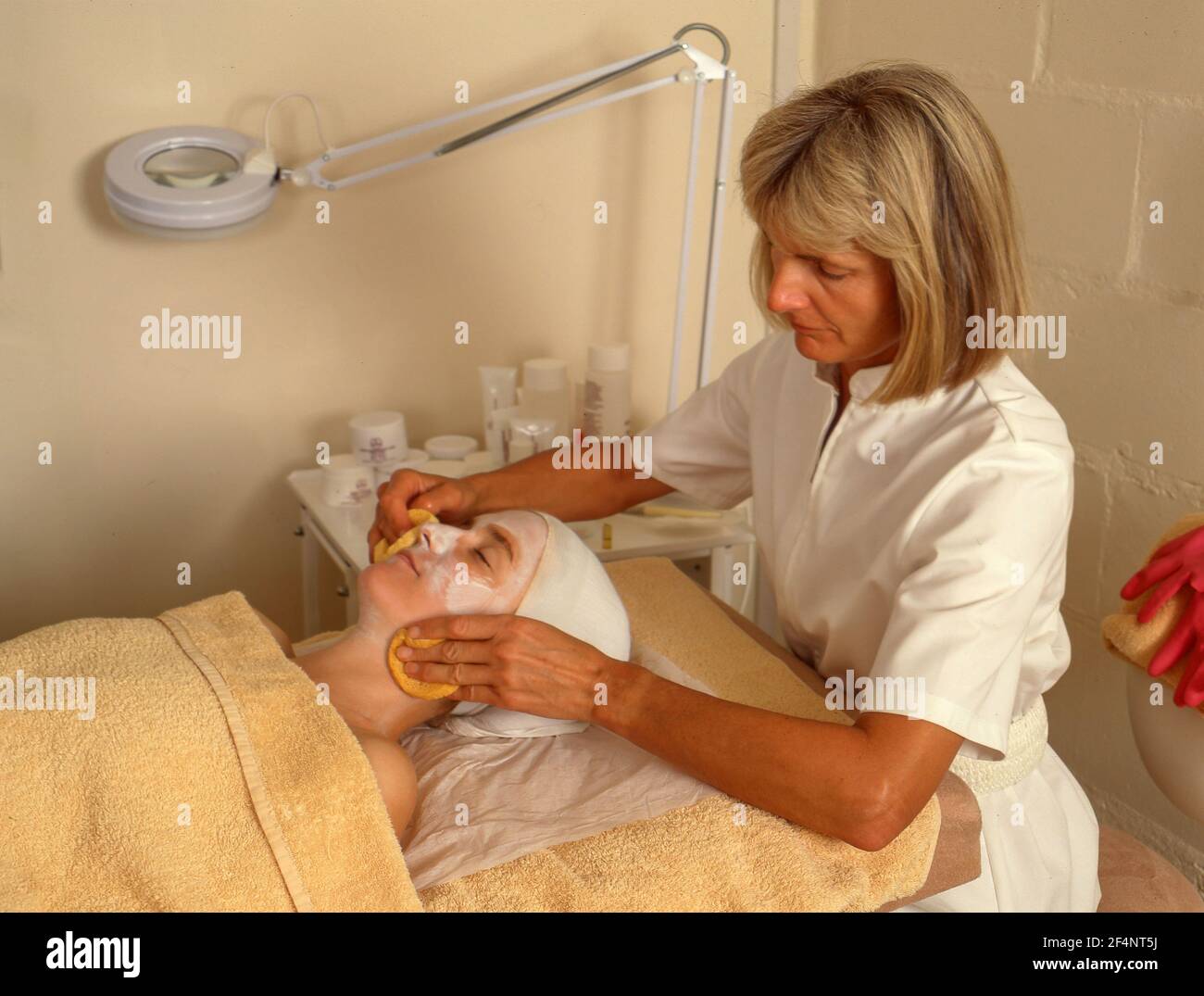 Beautican che fa massaggio facciale su giovane donna, Winkfield, Berkshire, Inghilterra, Regno Unito Foto Stock