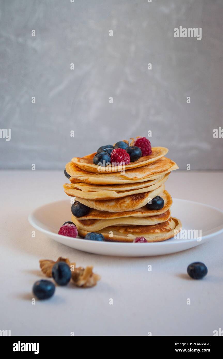 Deliziosi pancake appena cotti con miele, noce, lamponi e mirtilli per colazione. Foto Stock