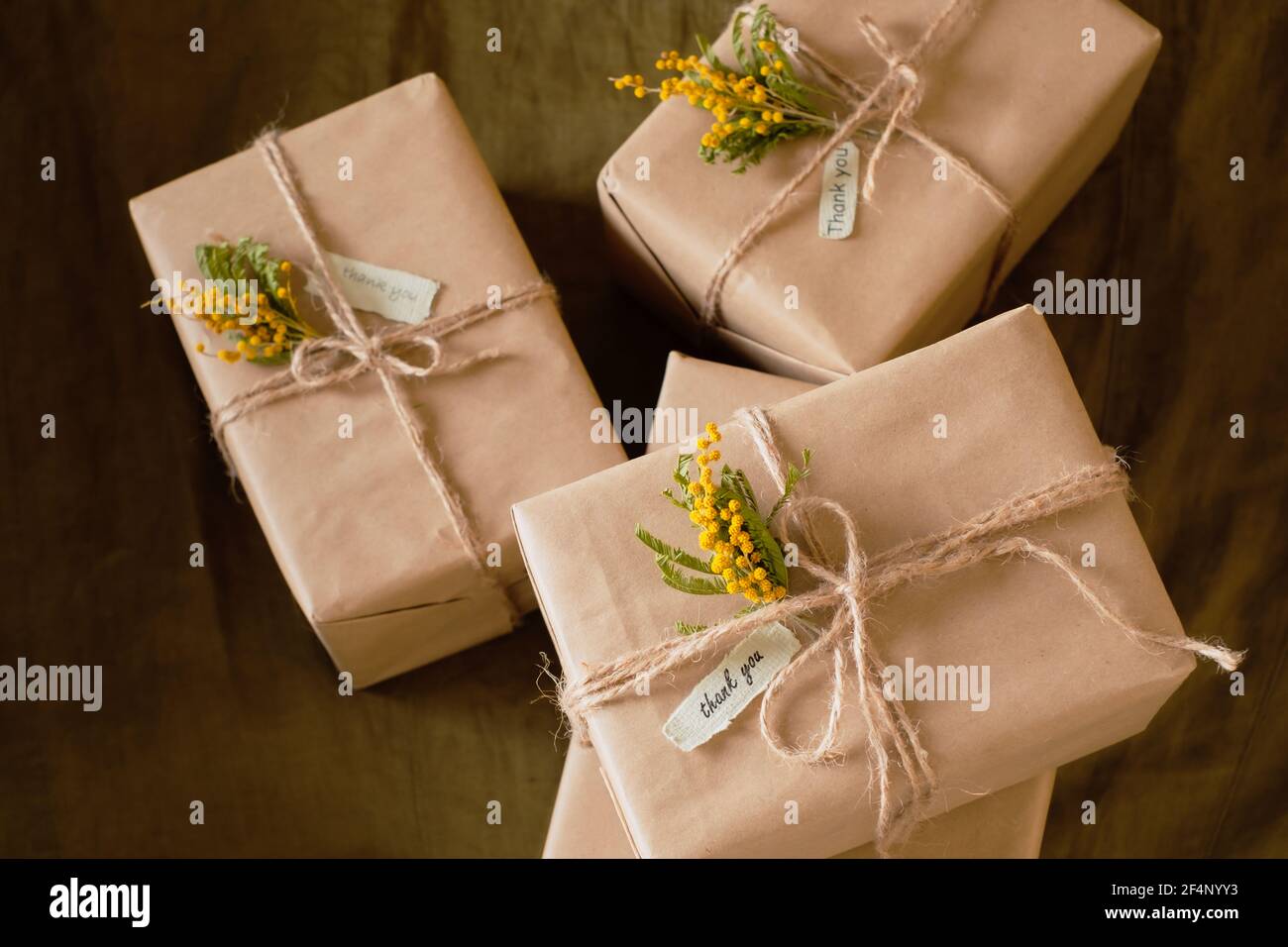 Immagine ravvicinata di una bella confezione regalo decorata con fiori gialli su uno sfondo scuro. Foto di alta qualità Foto Stock