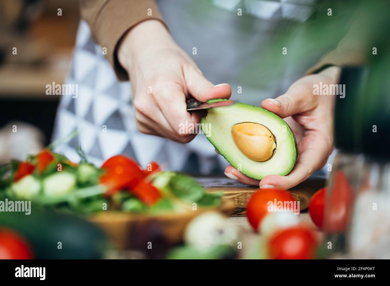 Donna che sbuccia un avocado per insalata. Vista ravvicinata. Foto Stock