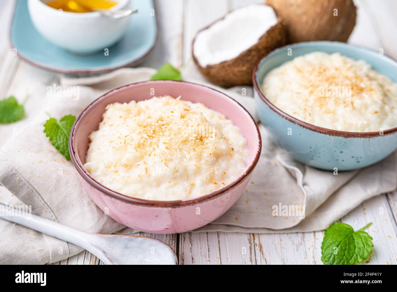 Dolce e cremoso budino di riso al cocco con miele, condito con cocco grattugiato e tostato in una ciotola in ceramica Foto Stock