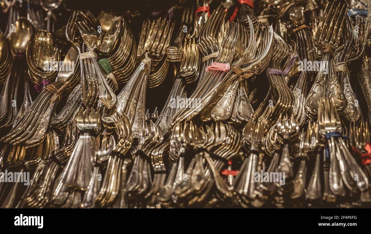 Sfondo di argenteria d'oro vintage: Cucchiai, cucchiaini da tè, forchette sulla mensola del mercato delle pulci. Messa a fuoco selettiva Foto Stock