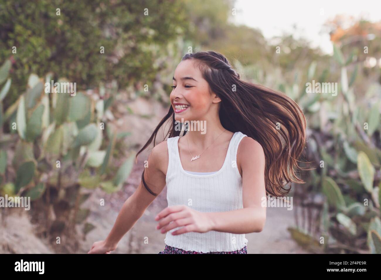 Misto razza ragazza che cammina su un percorso cactus con i suoi lunghi capelli volare. Foto Stock