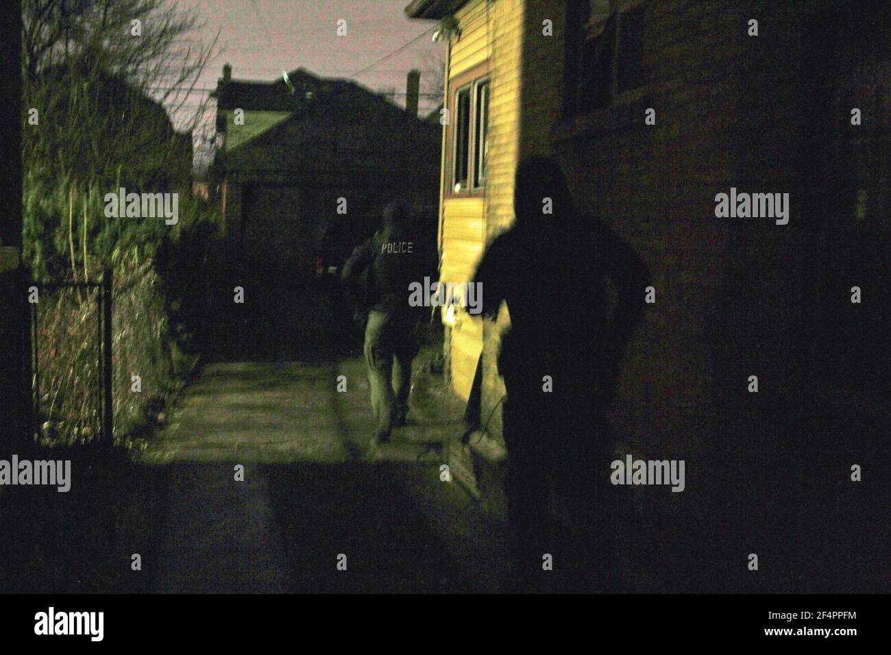 Gli agenti di polizia cercano il cortile posteriore di un edificio di notte, Detroit, Michigan, USA Foto Stock