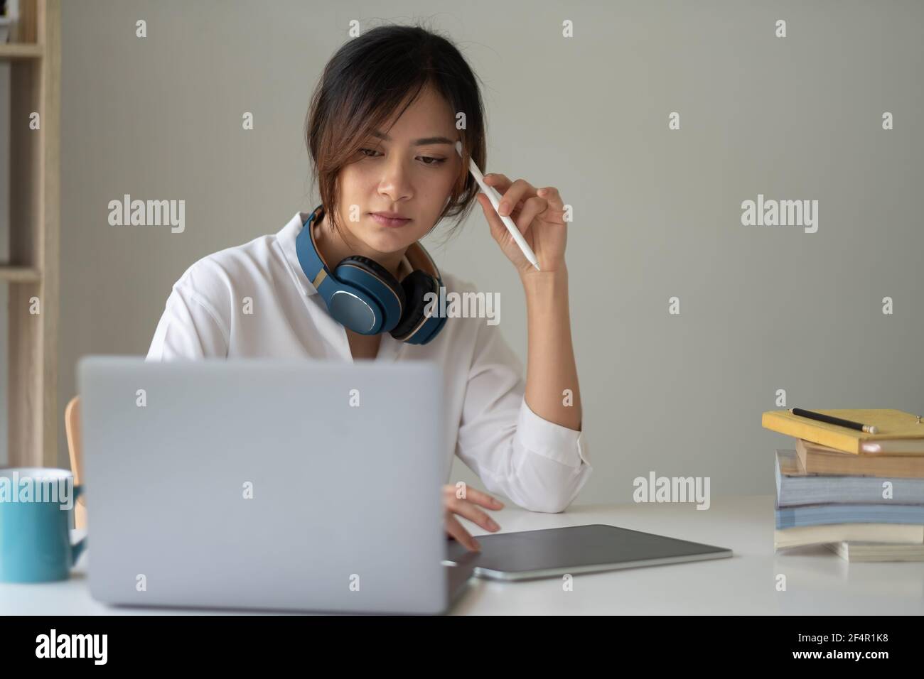 Giovane studentessa asiatica studia a casa usando il laptop e. apprendimento online Foto Stock