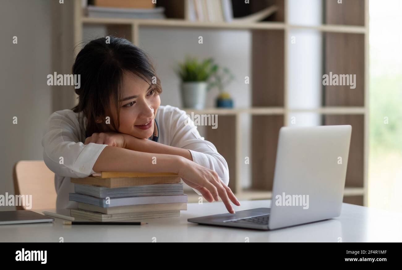 Giovane studentessa asiatica studia a casa usando il laptop e. apprendimento online Foto Stock