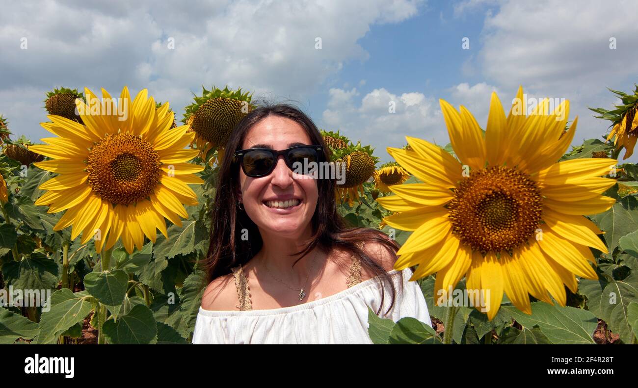 Allegra bella donna turca in occhiali da sole che posano su un girasole campo Foto Stock