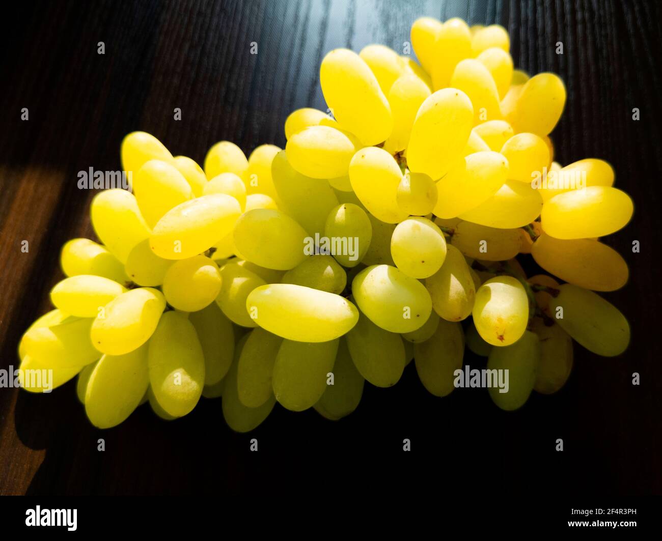 mazzo di uve fresche verdi isolato su sfondo ligneo Foto Stock