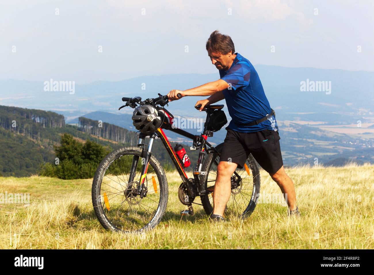 Uomo che cammina in bicicletta, uomo che spinge una mountain bike in salita Foto Stock