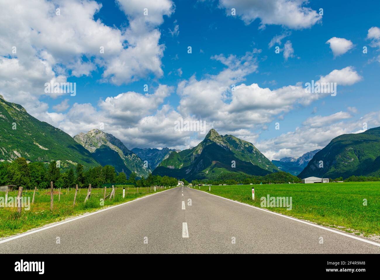 Strada asfaltata diritta attraverso i verdi pascoli in una splendida valle montana. Valle di Soca, Slovenia. La migliore destinazione d'Europa. Foto Stock