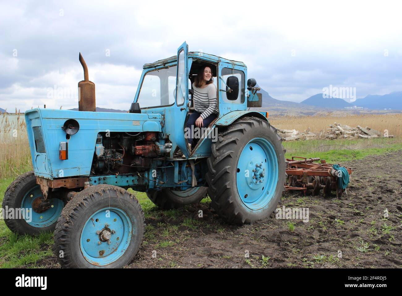 La ragazza sul trattore nel campo. Arare il terreno del trattore in autunno. Lavori agricoli. Foto Stock