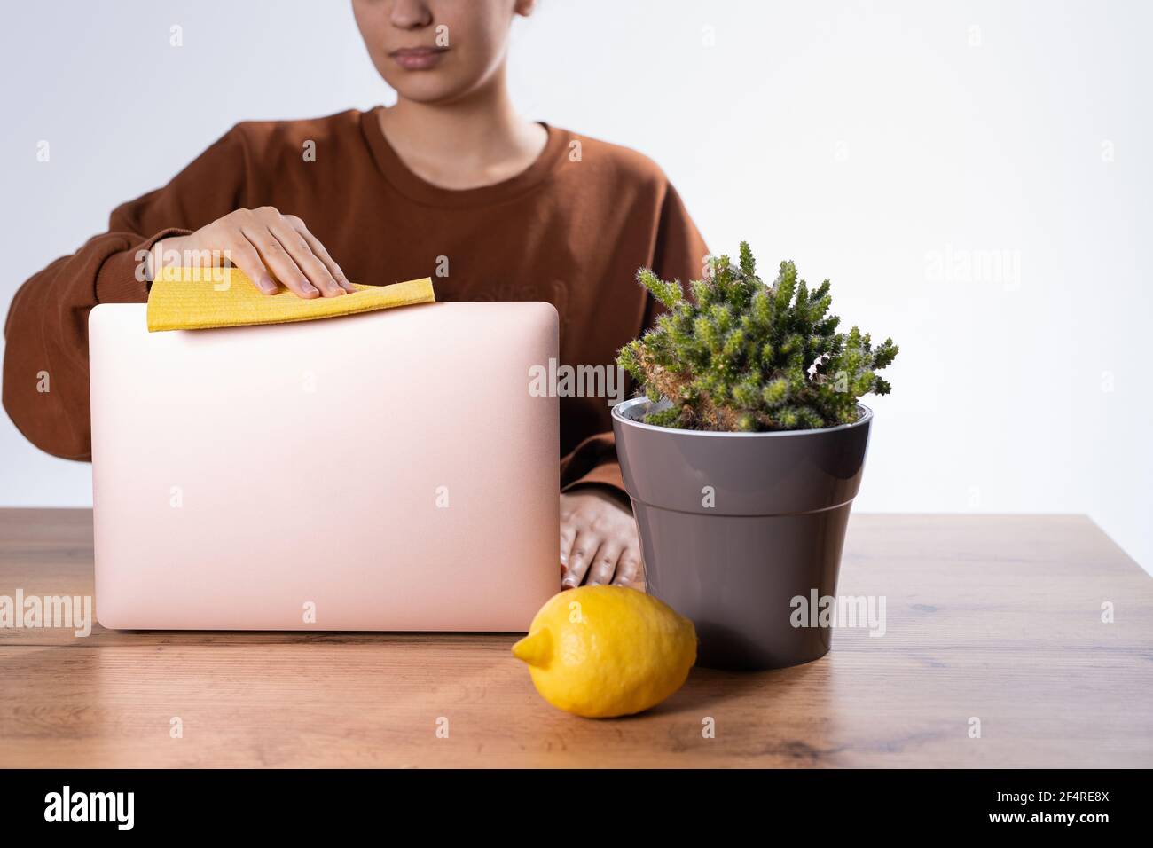 Giovane donna d'affari caucasica che utilizza igienizzante antisettico naturale, pulizia del monitor del computer prima di iniziare a lavorare in ufficio. Dipendente femminile Foto Stock