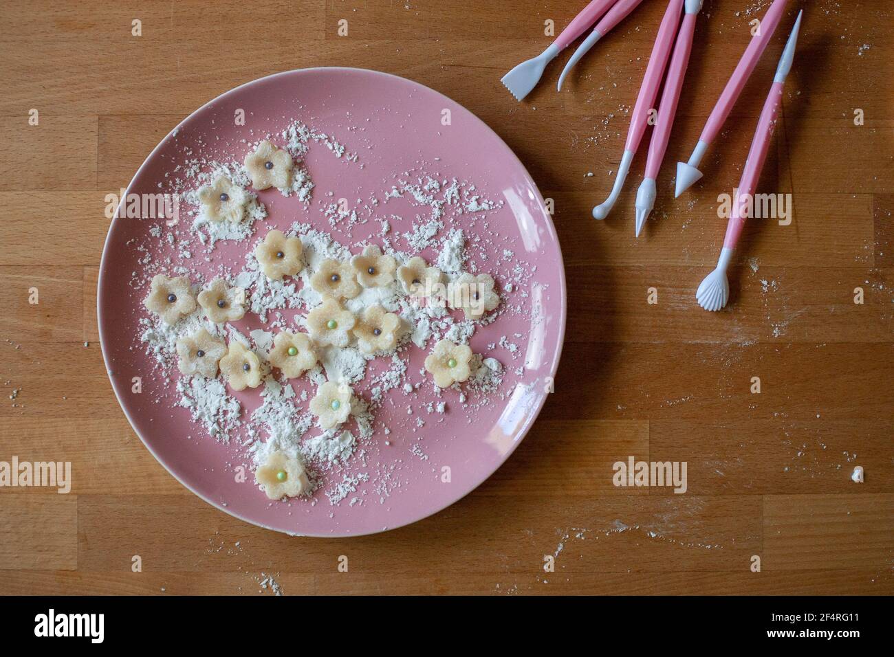 Fiori di marzapane bianchi preparati per la decorazione di torte con attrezzi fondenti e tagliabiscotti. Foto Stock