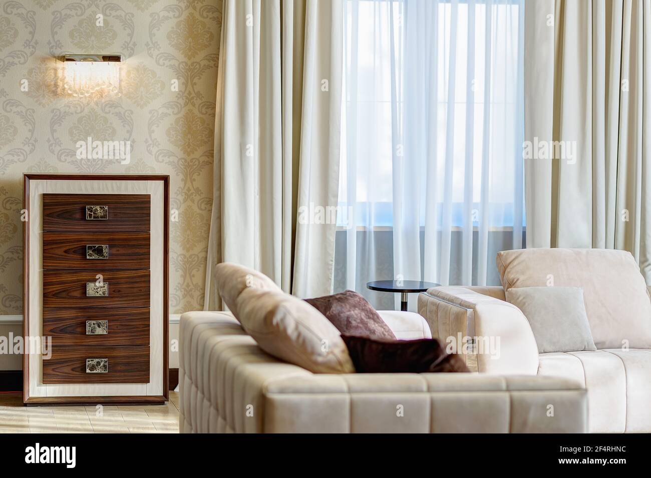 Interni moderni di soggiorno vuoto in marrone, bianco, marrone lithe, con motivi su sfondi di pareti. Due divani con grandi cuscini, coscia di legno Foto Stock