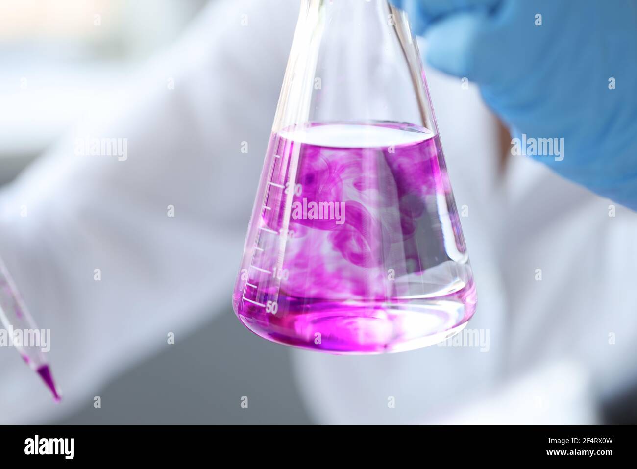 L'ostruzione della provetta con il liquido rosa in mano a scienziato Foto Stock