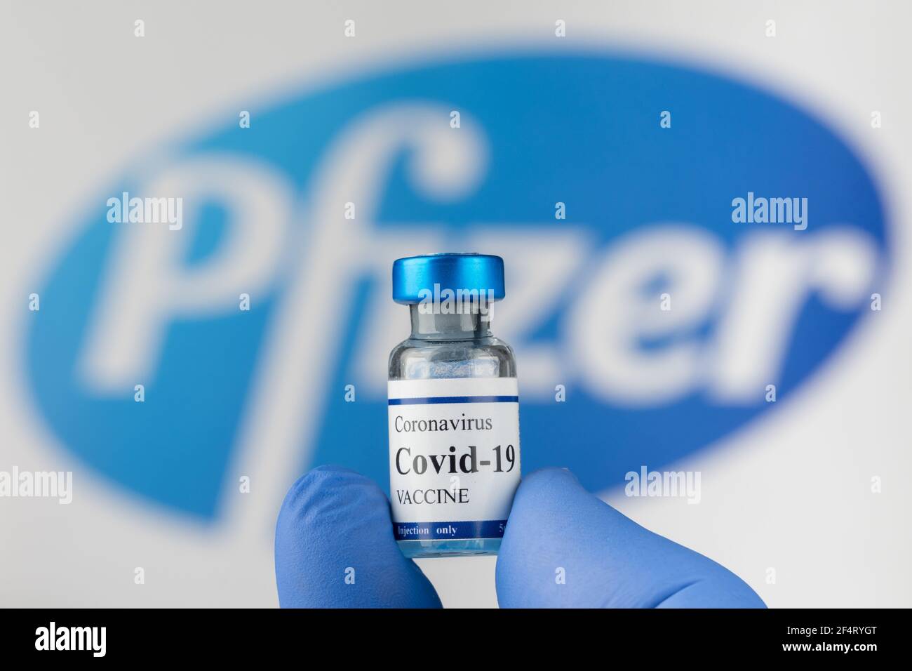 La mano del medico in guanti di lattice blu contiene il flaconcino di vaccino del coronavirus Covid-19. Foto Stock