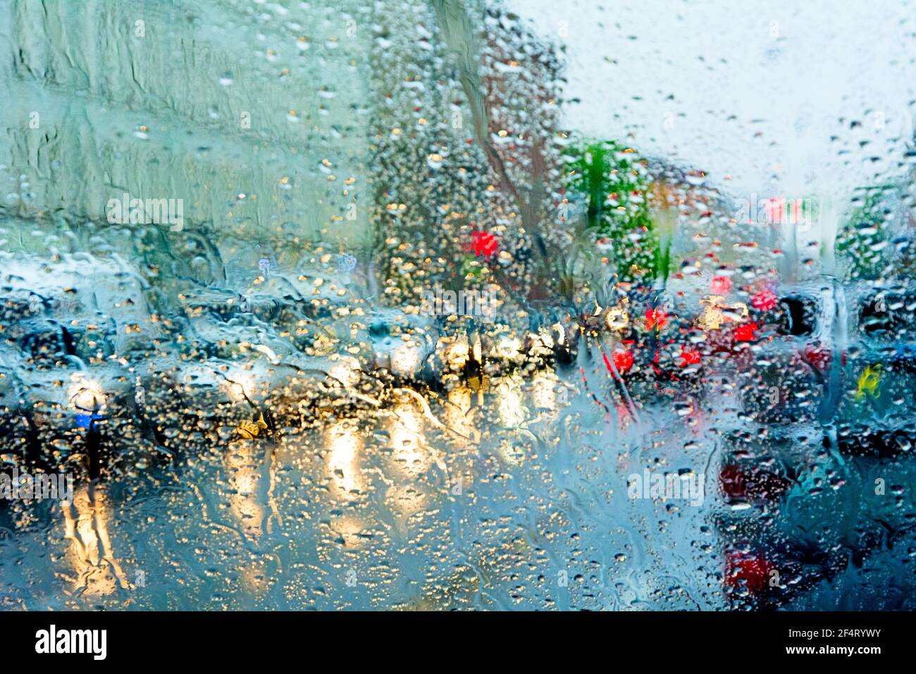 Maltempo, pioggia, traffico di strada fotografato attraverso il vetro bagnato. Foto Stock