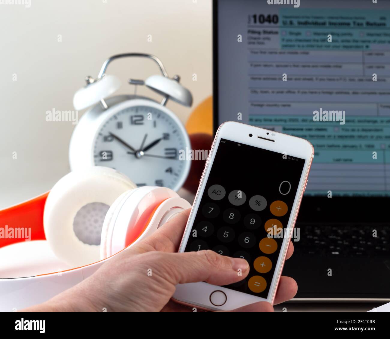 Kiev, marzo 2021. Mano con una calcolatrice sul telefono. Computer con modulo fiscale degli Stati Uniti 1040. Concetto di giorno fiscale. Foto Stock