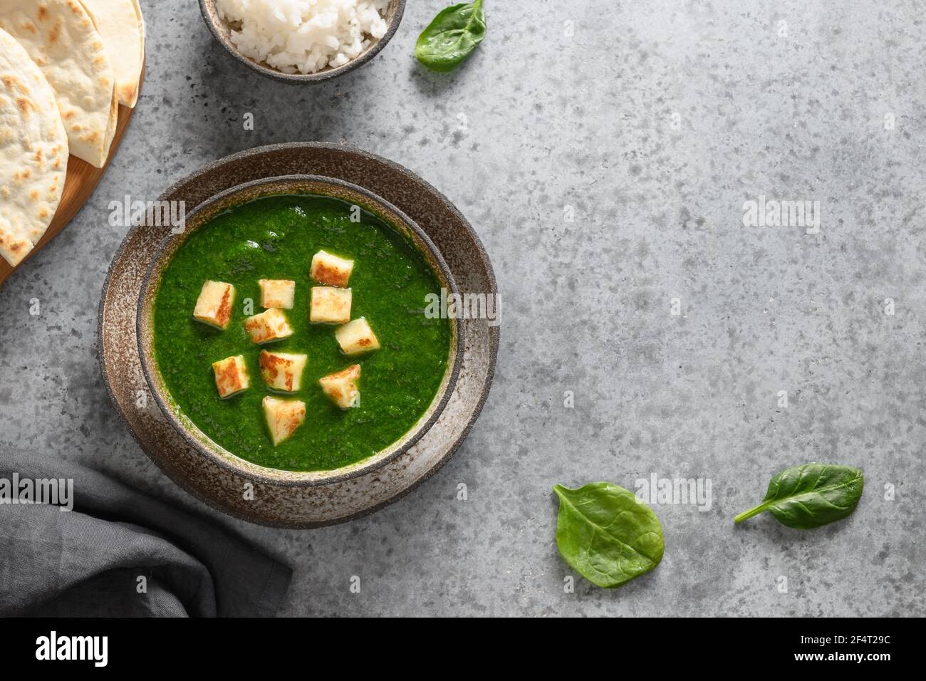Palak Paneer servito con riso basmati su fondo di pietra grigia. Cucina vegetariana indiana a base di spinaci e formaggio paneer. Spazio di copia. Vista da abo Foto Stock