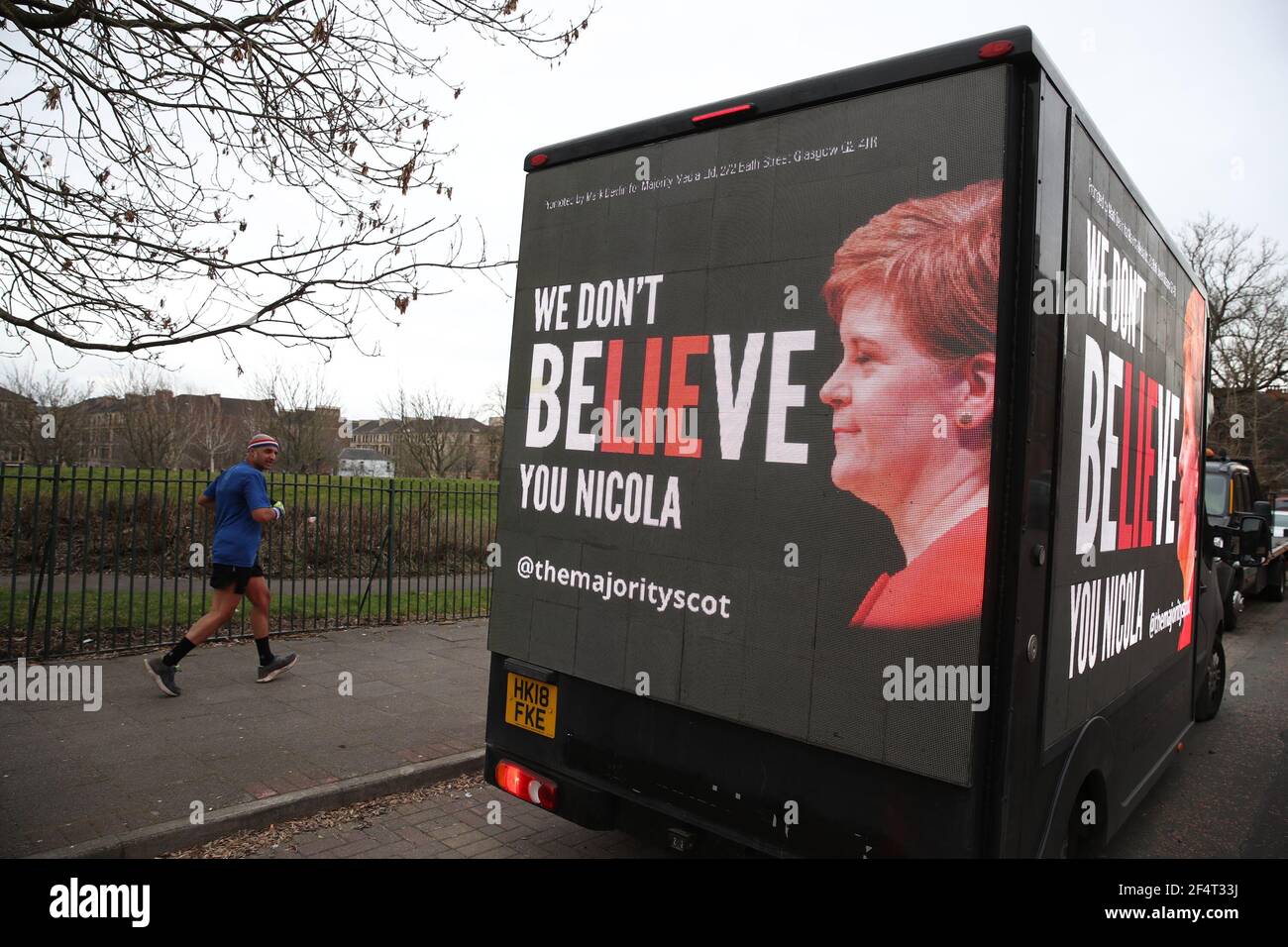Un uomo si accanisce davanti a un tabellone mobile che dice 'non ci crediamo Nicola' mentre guida attraverso la circoscrizione del primo ministro Nicola Sturgeon a Govanhill, Glasgow, come parte della campagna di ResignSturgeon della maggioranza nella corsa alle elezioni scozzesi del 6 maggio. Data immagine: Martedì 23 marzo 2021. Foto Stock