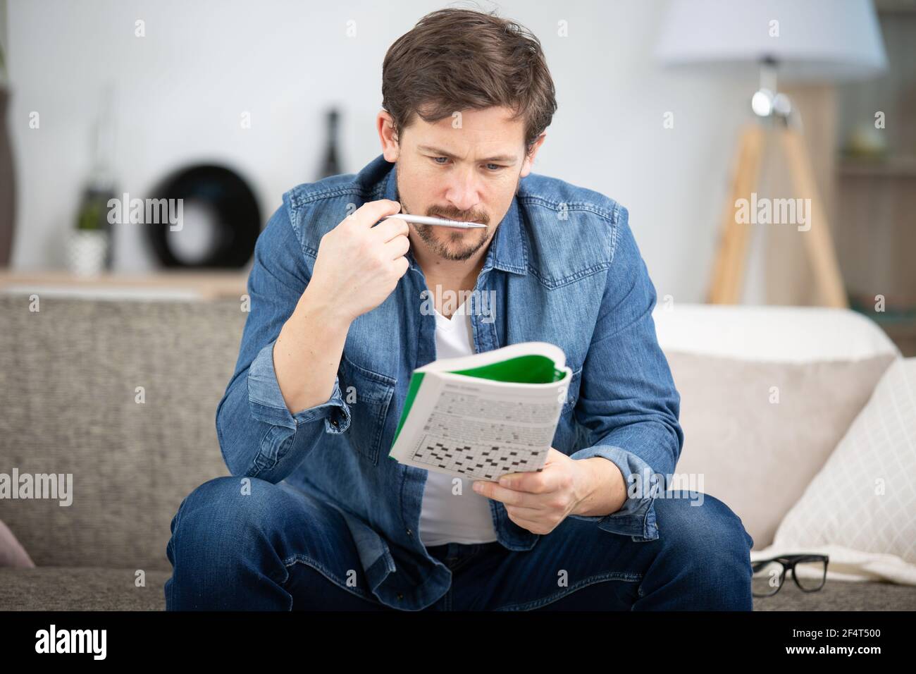 giovane uomo seduto facendo un puzzle crossword Foto Stock