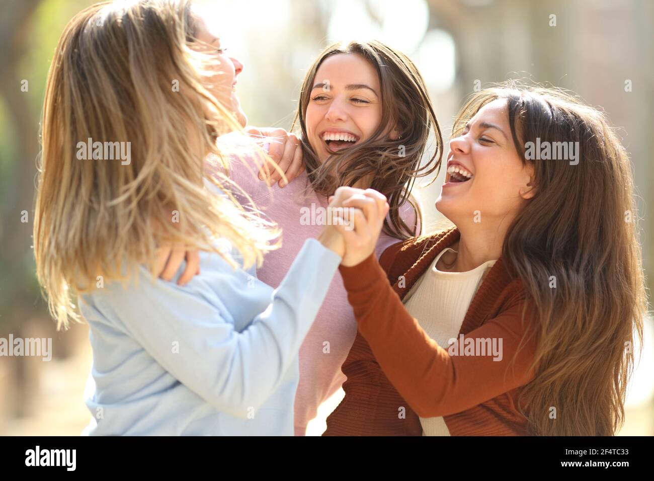 Tre amiche eccitate che saltano celebrando la felicità per strada Foto Stock