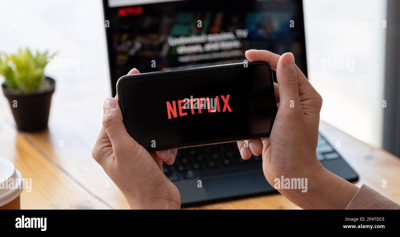 CHIANG mai, THAILANDIA - MAR 21, 2021 : Donna con iPhone X aprire applicazione Netflix a casa. Netflix è un fornitore globale di film in streaming e TV Foto Stock