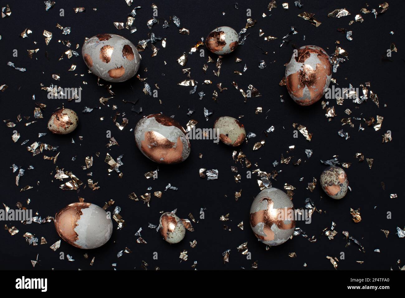 Uova dorate e confetti luminosi su sfondo nero. Foto Stock