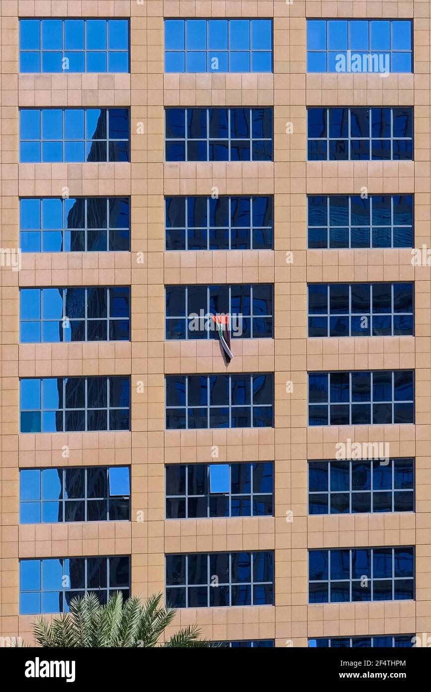 Bandiera nazionale Emirati Arabi Uniti e finestre. Enorme bandiera degli Emirati Arabi Uniti appesa a una finestra di un moderno edificio di uffici nel centro di Abu Dhabi.Emirati Arabi Uniti. Foto Stock