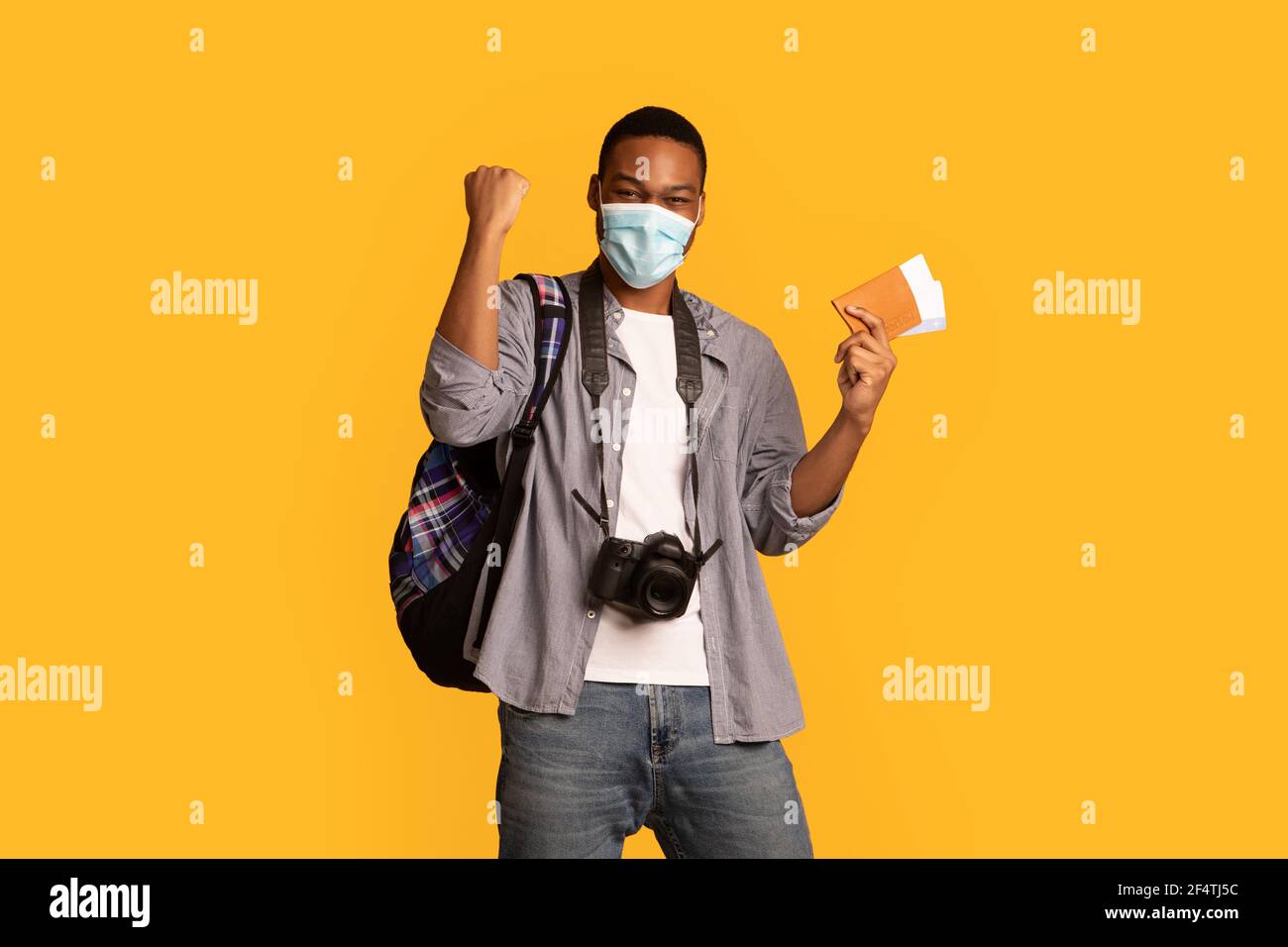 Felice entusiasta guy del turista africano in maschera medica con passaporto In mano Foto Stock