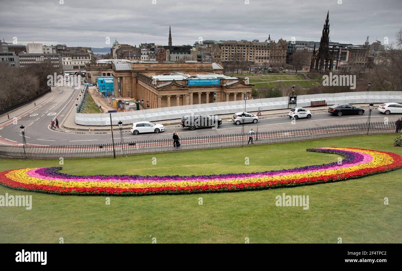 Centro di Edimburgo, Scozia, Regno Unito. 23 marzo 2021. "National Day of Reflection" (Giornata nazionale della riflessione) nell'anniversario della prima chiusura del Covid-19 del Regno Unito. Arcobaleno floreale di speranza a Mound, I coltivatori scozzesi per conto dell'industria orticola scozzese hanno offerto le piante che provenivano dalla Valle di Clyde nelle prime ore della mattina del 22 marzo per piantare un arcobaleno di 20 m di primerote per ricordare a tutti noi la gioia che il giardinaggio può portare. Oltre 12,000 piante coltivate in Scozia, sono usate per creare il pezzo stupefacente, costruito dal personale del comune di Edimburgo. Credit: Arch whiter/Alamy Live News. Foto Stock