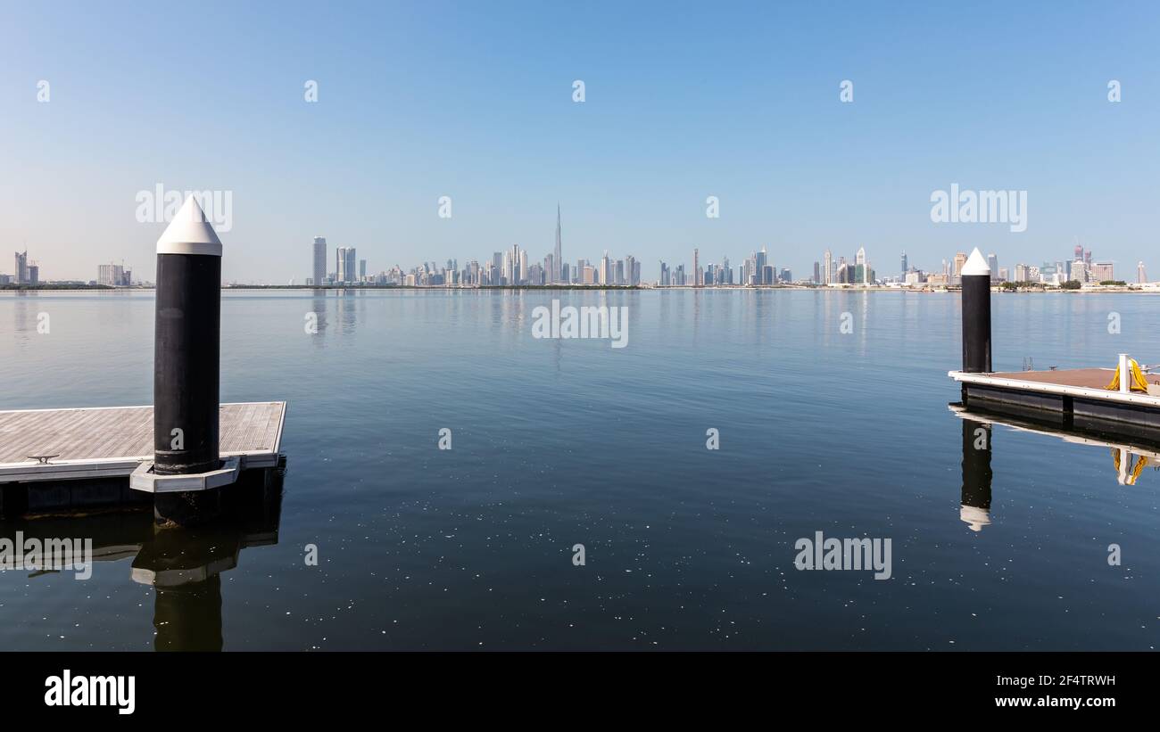 Panorama dello skyline del centro di Dubai con moli e pali galleggianti in legno in primo piano, visti dalla passeggiata del Porto di Dubai Creek. Foto Stock