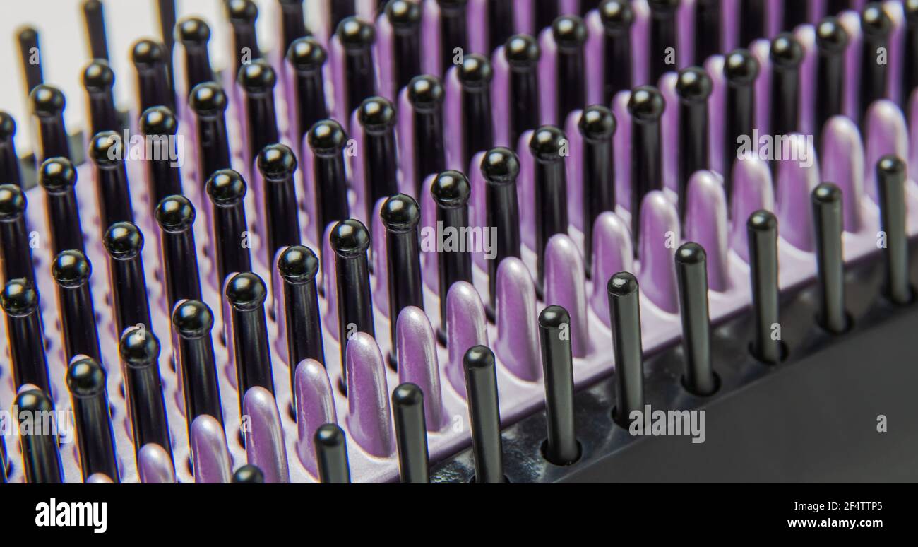 Spazzola per capelli termoelettrica nera con setole viola. Fotografia macro. Immagine di sfondo Foto Stock