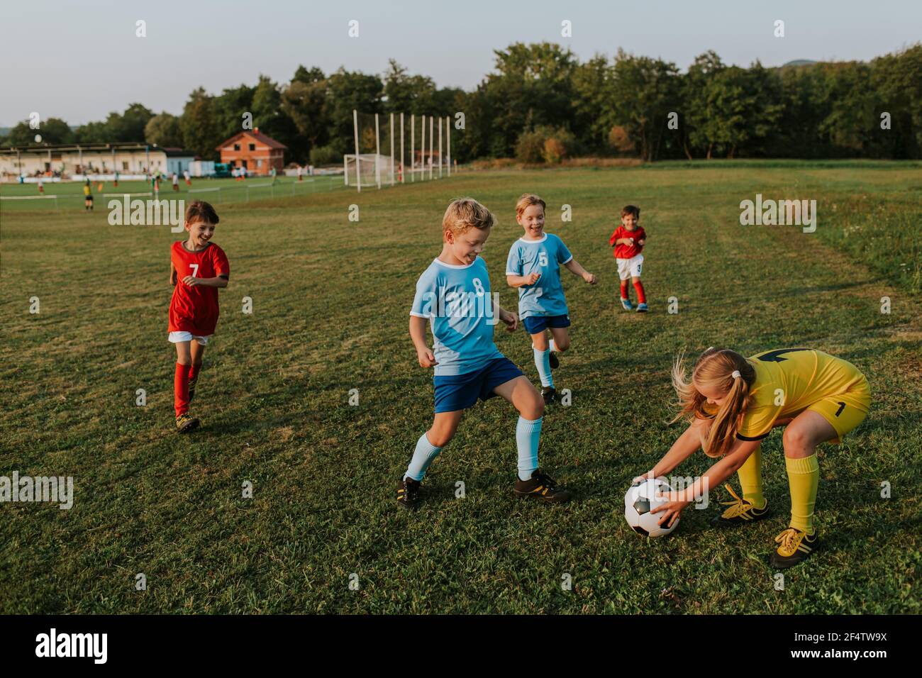 Bambini che giocano a calcio all'esterno. Portiere ragazza che cattura palla di calcio alla concorrenza dilettante. Foto Stock