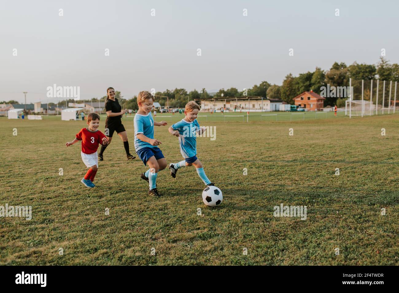 Bambini che giocano a calcio. Gruppo di giocatori di calcio felici che corrono dopo la palla sul campo. Foto Stock