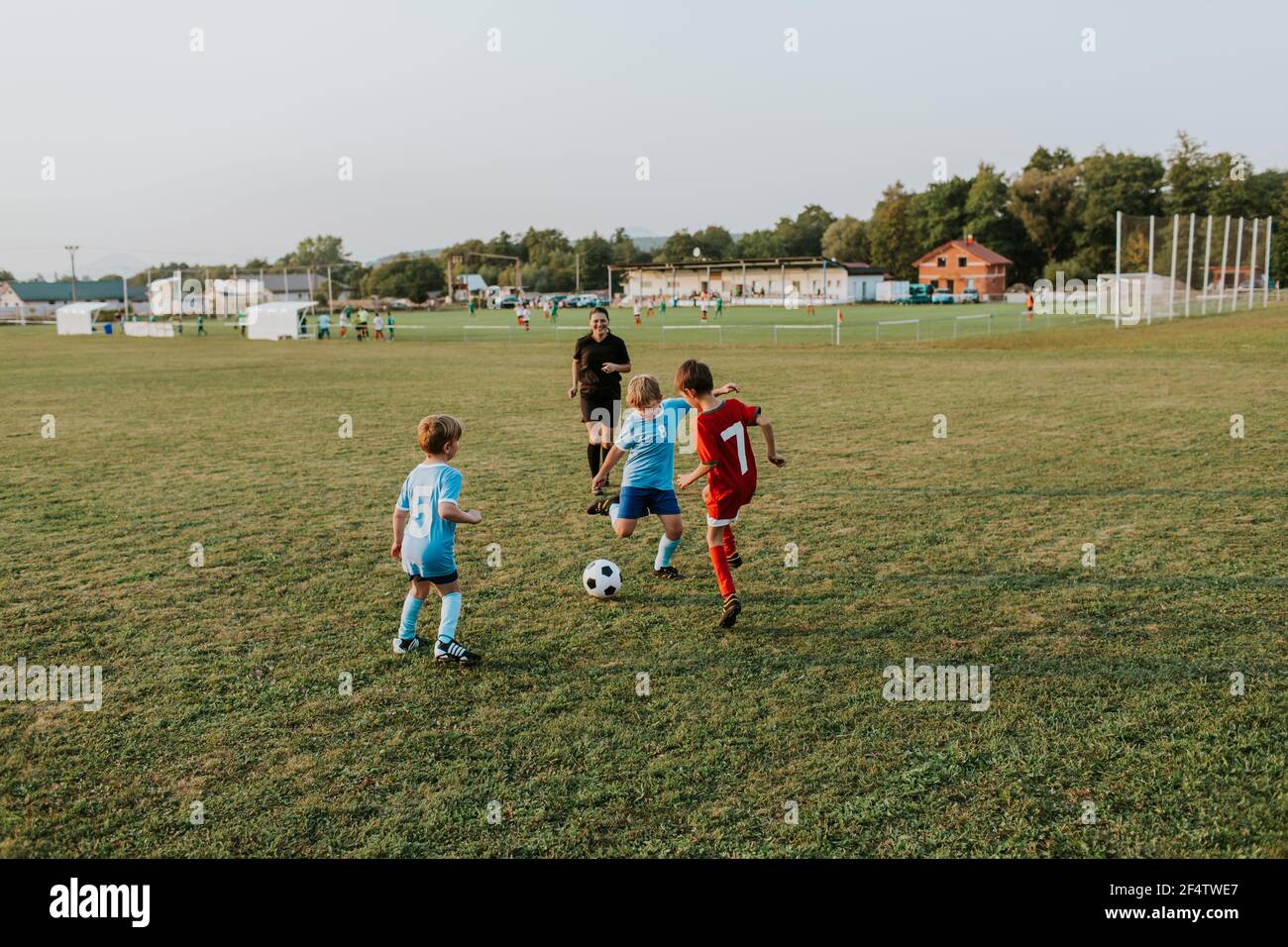 Bambini che giocano a calcio. Ragazzi in abiti da calcio che corrono dopo la palla sul campo. Foto Stock