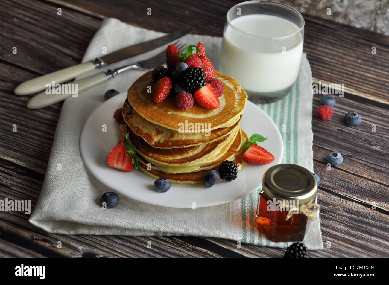 Colazione fatta in casa con pancake, latte e miele. Foto Stock