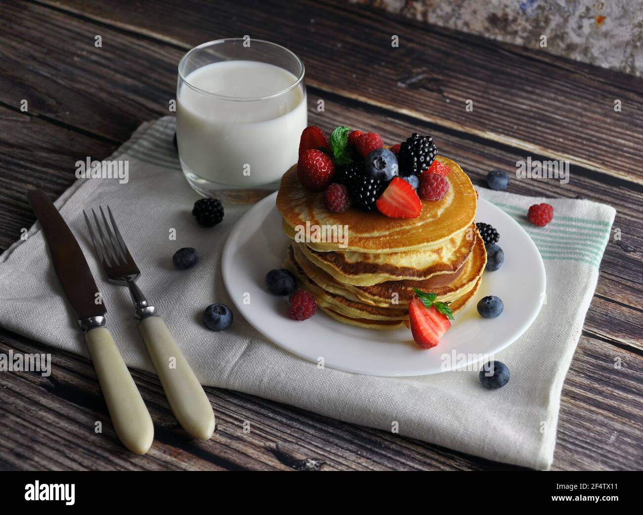 Sana colazione di frittelle con frutti di bosco, latte su un asciugamano da cucina. Foto Stock