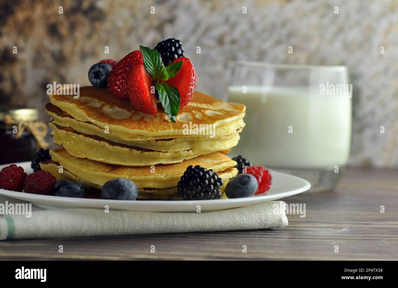 Un piatto di pancake primo piano sul tavolo. Latte e miele sullo sfondo. Vista laterale. Foto Stock