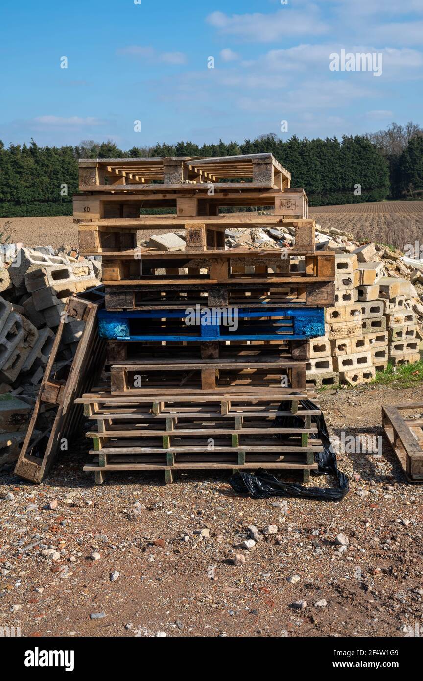 Una pila di pallet di legno uno sopra l'altro con un mucchio di macerie di mattone dietro con alcuni mattoni con fori Foto Stock