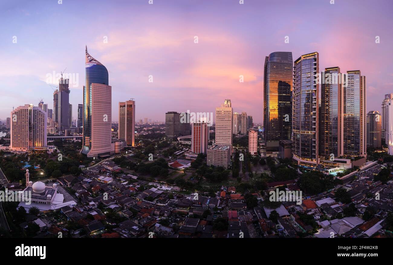 Tramonto mozzafiato sullo skyline di Giacarta, dove le moderne torri di uffici e condomini contrastano con il villaggio tradizionale, chiamato Kampung, in Indonesia capit Foto Stock