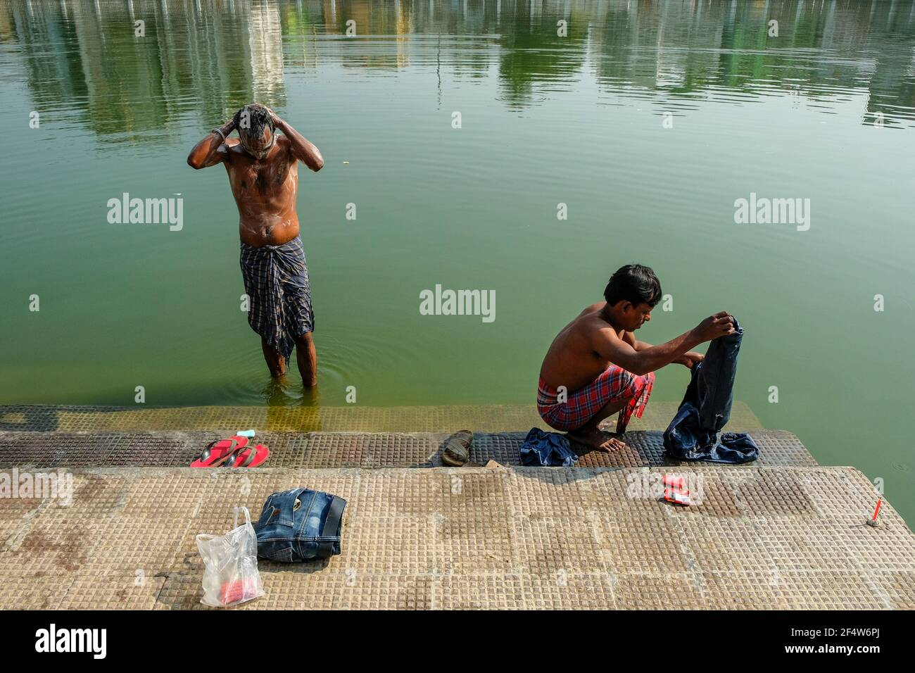 Agartala, India - 2020 dicembre: Un uomo che lavano i vestiti nel lago di Rajbari del palazzo di Ujjyanta il 19 dicembre 2020 ad Agartala, Tripura, India. Foto Stock