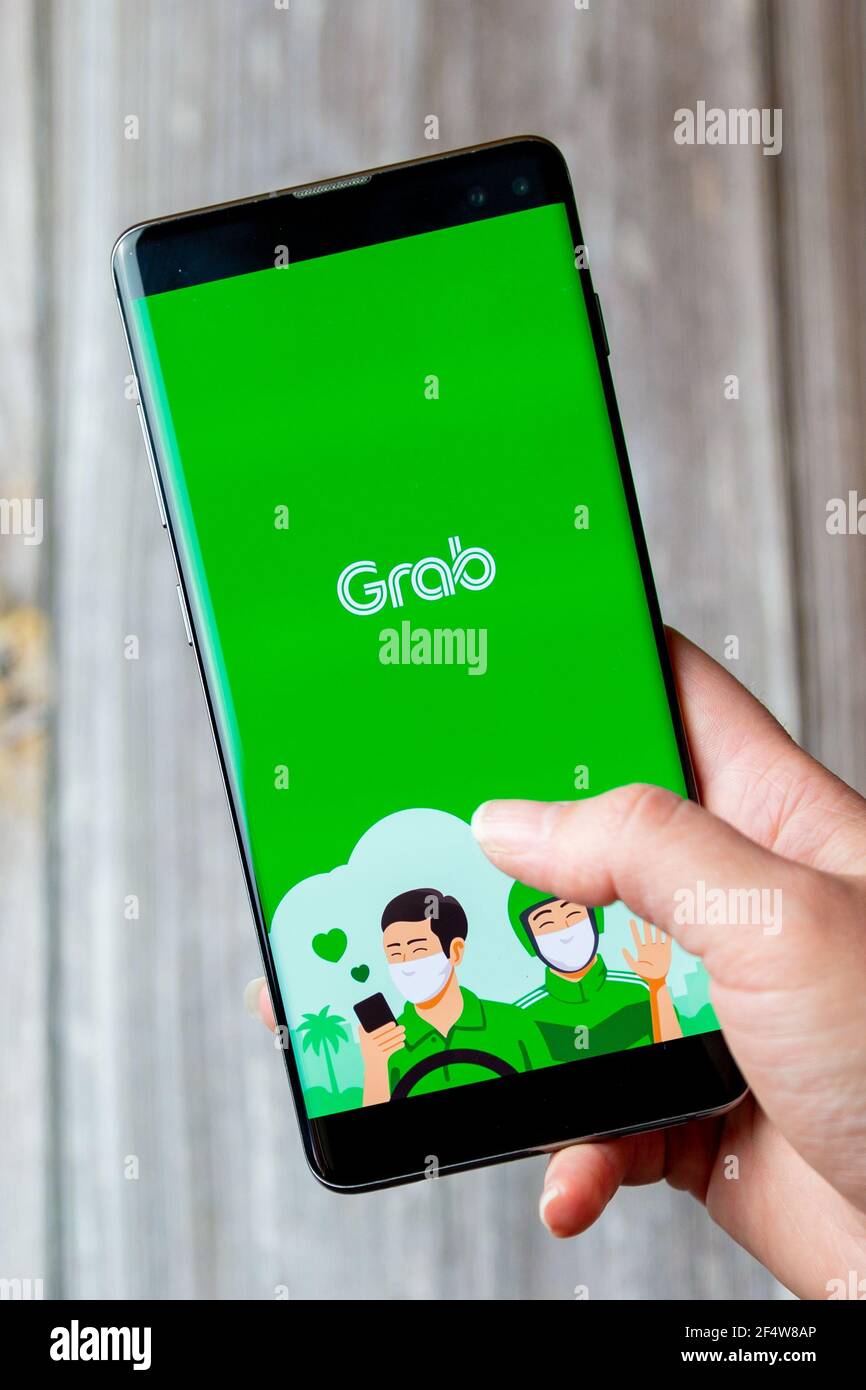 Un telefono cellulare o un telefono cellulare in attesa in un Mano con l'app Grab aperta sullo schermo Foto Stock