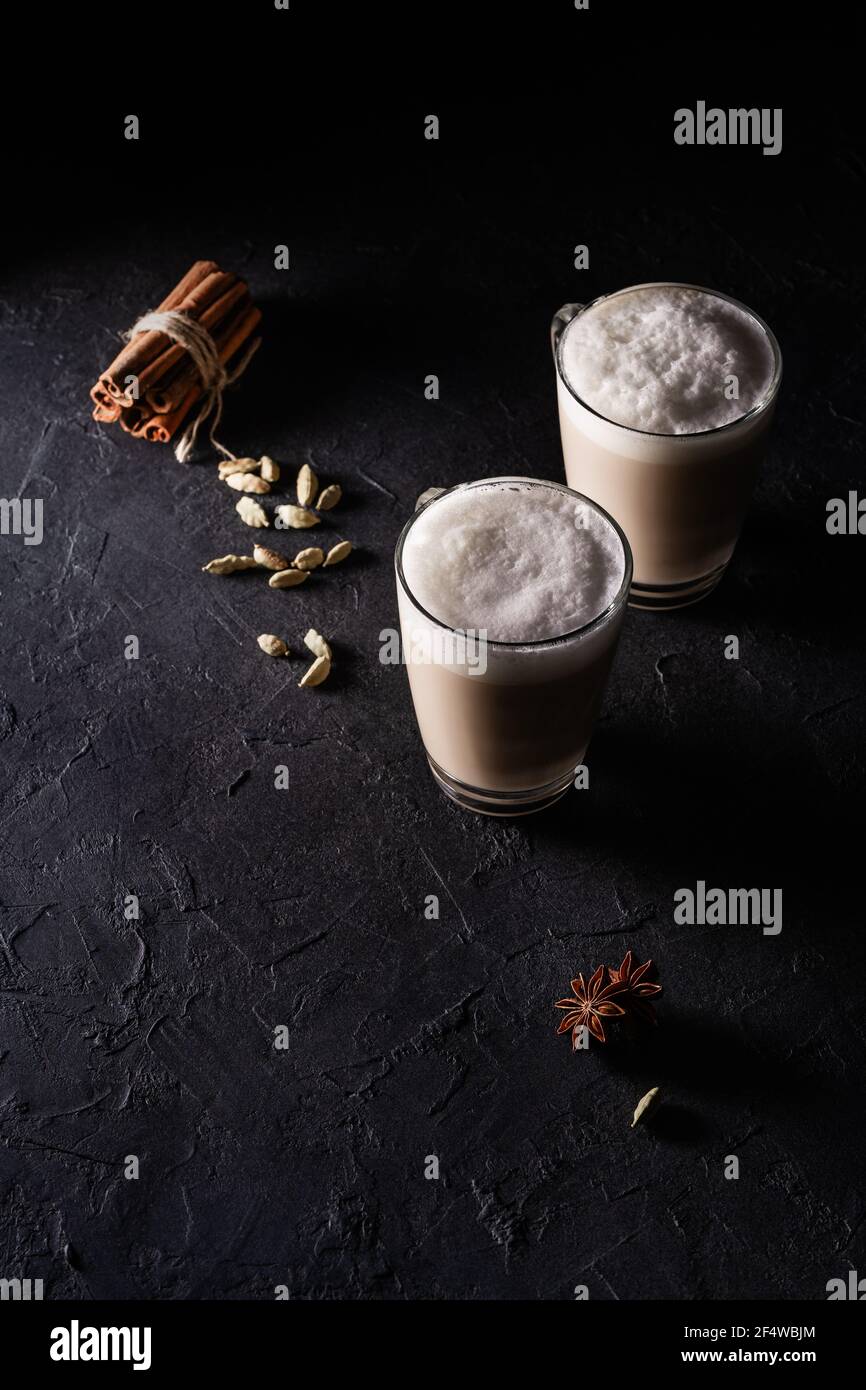 Due tazze di latte di tè Chai, tè caldo con latte espanso su sfondo nero scuro Foto Stock