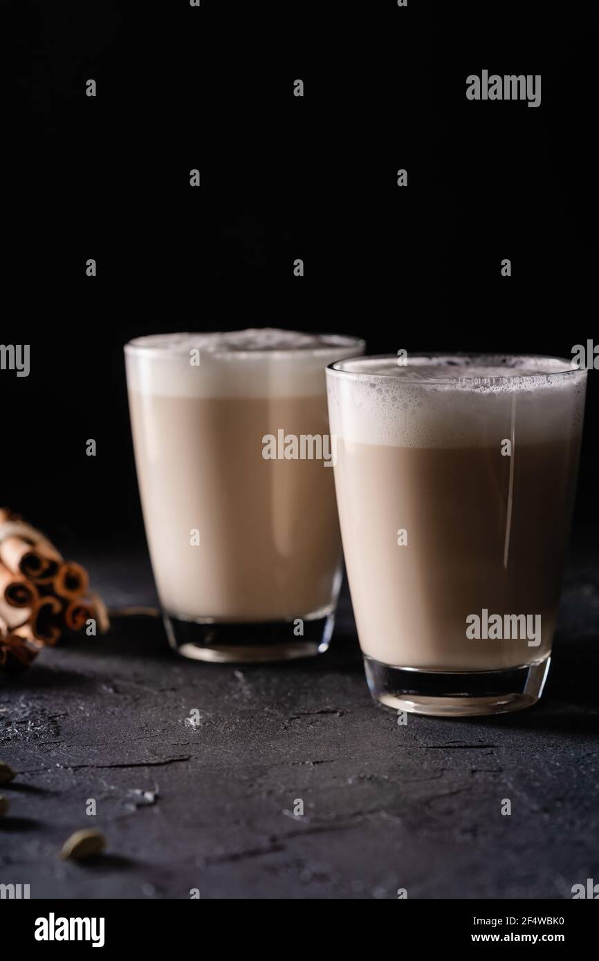 Due tazze di latte di tè Chai, tè caldo con latte espanso su sfondo nero scuro Foto Stock