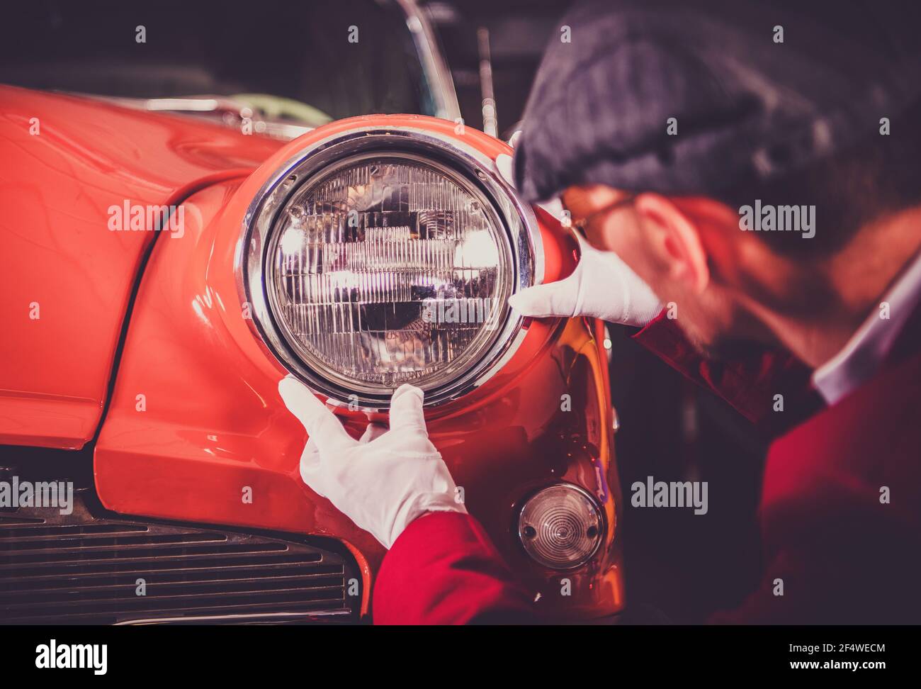 Hobbista caucasico in guanti bianchi Restoring Arancio scuro rossastro Body Vintage Car. Controllo dei fari anteriori. Auto classiche e settore automobilistico tema. Foto Stock