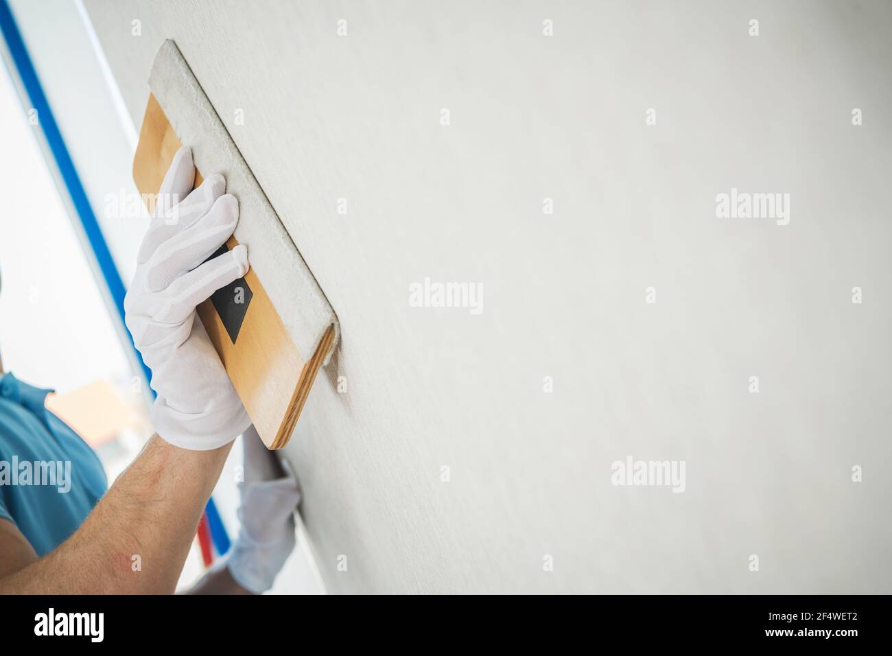Vinil Wallpapers cigolio strumento in uso da professionista caucasico Interior Renovation Worker. Foto Stock